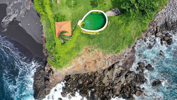 Top view of swimming pool on the cliff edge with the view of the ocean. Uluwatu, Bali, Indonesia. Aerial view of an amazing place on the rock cliff and coastline. Destination for holiday - Photo, Image