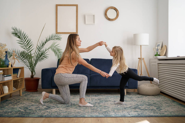 Glücklich fitte sportliche Mutter und lustige aktive Tochter haben Spaß beim gemeinsamen Tanzen zu Hause - Foto, Bild