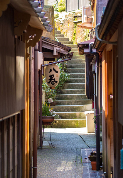 Kleine Seitenstraße zwischen traditionellen Holzhäusern im historischen Hagashiyama-Viertel von Kanazawa, Präfektur Ishikawa, Westjapan. ÜBERSETZUNG VON TEXT AUF LANTERN: hachimaki oder Stirnband. - Foto, Bild