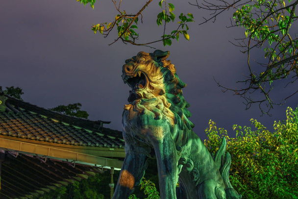 Vista nocturna del perro león, o komainu, en el santuario de oyama jinja, Kanazawa, Ishikawa, Japón. Estas estatuas tradicionales se ven a menudo en parejas en la mayoría de los santuarios y están destinadas a alejar a los espíritus malignos. - Foto, imagen