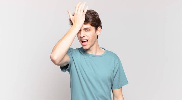young boy raising palm to forehead thinking oops, after making a stupid mistake or remembering, feeling dumb - Фото, изображение