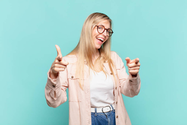 young blond pretty woman smiling with a positive, successful, happy attitude pointing to the camera, making gun sign with hands - Fotografie, Obrázek
