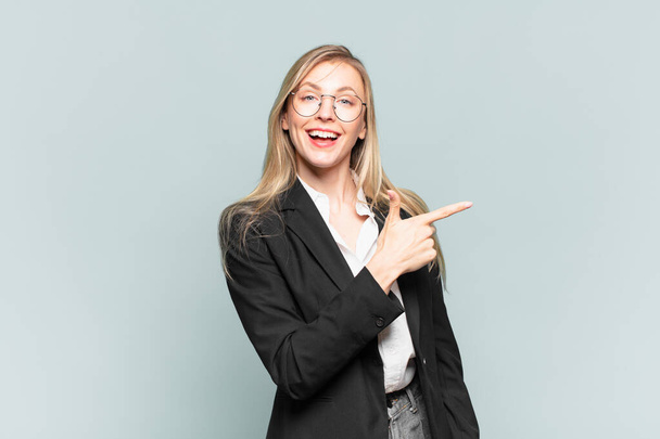young pretty businesswoman looking excited and surprised pointing to the side and upwards to copy space - Foto, imagen