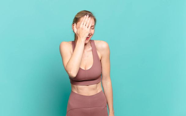 young blond woman laughing and slapping forehead like saying doh! I forgot or that was a stupid mistake. sport concept  - 写真・画像