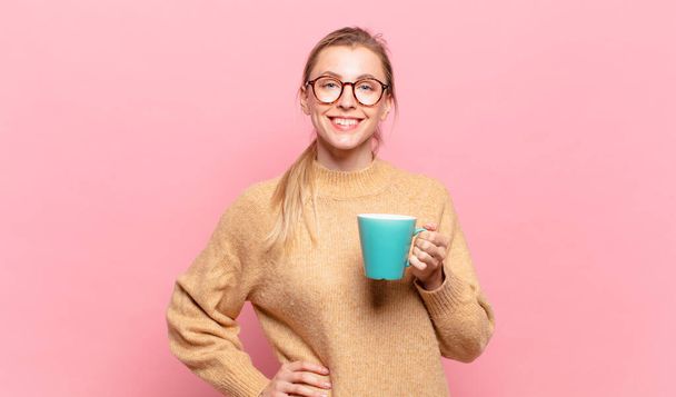 young blond woman smiling happily with a hand on hip and confident, positive, proud and friendly attitude. coffee concept - Φωτογραφία, εικόνα