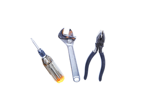 Un conjunto de herramientas, destornillador, alicates y llave ajustable sobre fondo blanco
. - Foto, imagen