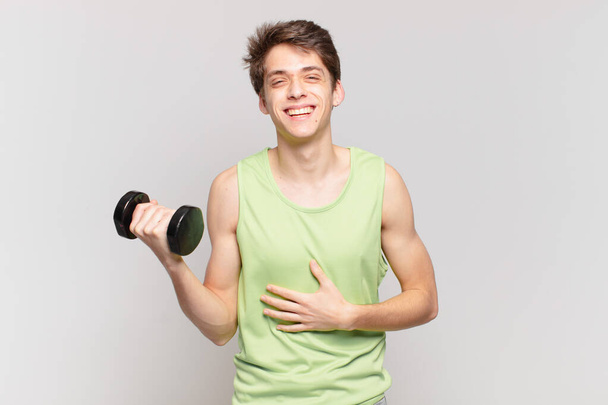 young boy laughing out loud at some hilarious joke, feeling happy and cheerful, having fun. dumbbell concept - Фото, зображення