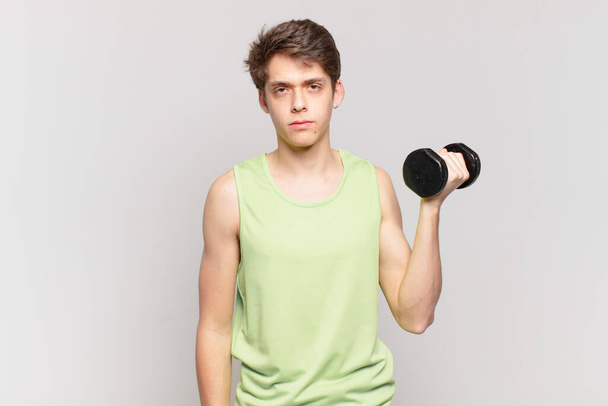 young boy feeling sad, upset or angry and looking to the side with a negative attitude, frowning in disagreement. dumbbell concept - Photo, Image