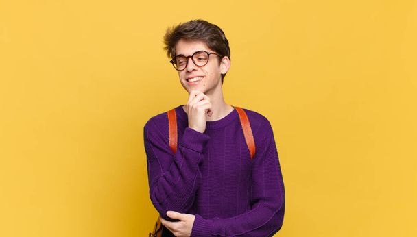 young student boy smiling with a happy, confident expression with hand on chin, wondering and looking to the side - Foto, Imagen
