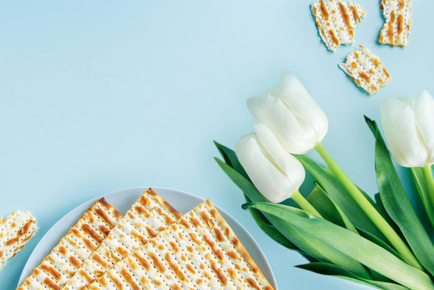 Feliz concepto de la Pascua. Matzo y tulipanes blancos sobre fondo azul. Fiesta judía religiosa Pesaj. Copiar espacio, plano laico. - Foto, imagen