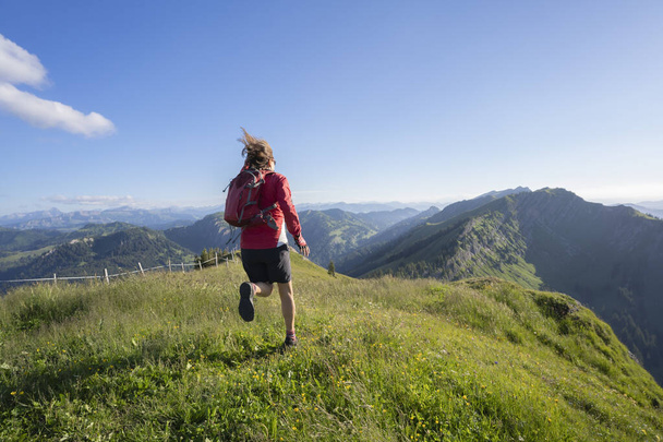 mujer mayor activa montaña corriendo por la noche temprano en la luz cálida del amanecer en la cresta de la cadena Nagelfluh en los Alpes Allgau cerca de Immenstadt, Baviera, Alemania - Foto, imagen
