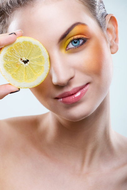 レモンと黄色の化粧品で美しい女性 - 写真・画像