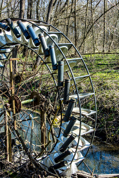 Металлическое колесо с лезвиями для откачки воды по реке в лесу. - Фото, изображение