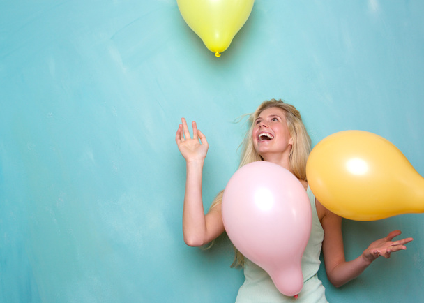 Молодая женщина улыбается и играет с воздушными шарами
 - Фото, изображение