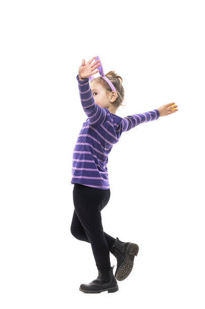 Боковой вид беззаботной игривой юной девушки, бегающей как летающая с распростертыми объятиями. Полное тело изолировано на белом фоне - Фото, изображение