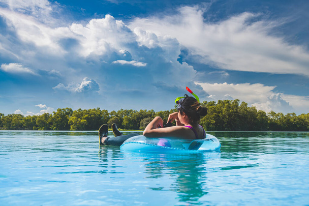 Woman on the doughnut swimming ring in the nature pool with outdoor clouds lighting. - Photo, Image