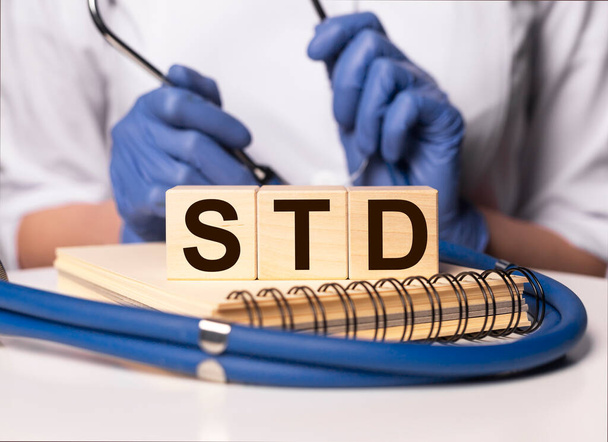 STD acronym inscription on wooden cubes in doctor hands. - Valokuva, kuva