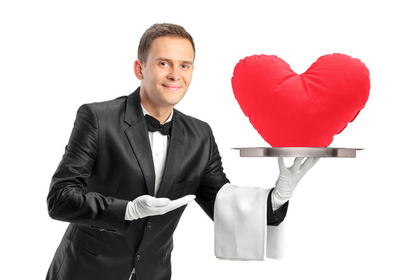 Butler holding a tray with a red heart shape object on it - Foto, immagini