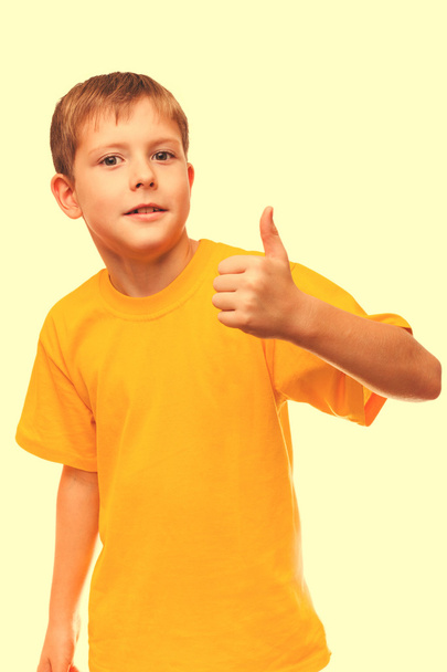 Blond boy kid in yellow shirt holding a thumbs-up, showing the s - Foto, immagini