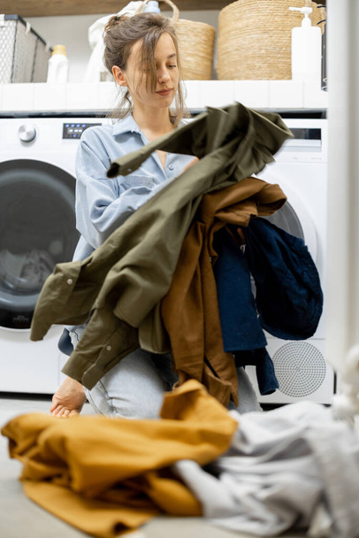 Gospodyni domowa sortuje brudne ubrania w pralni - Zdjęcie, obraz