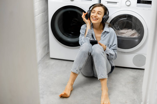 Woman enjoys music while washing clothes - Photo, Image
