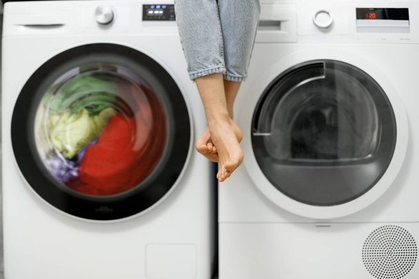 Mujer sentada sobre las lavadoras y secadoras - Foto, imagen