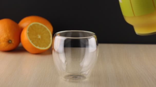 Orangensaft aus Glas in Glas gießen. Schließen Sie ein Glas frischen Orangensaft. Zubereitung eines gesunden Frühstücks aus natürlichen Zutaten. Hausgemachter Fruchtsaft auf dem Tisch. Bio-Vitamingetränk - Filmmaterial, Video