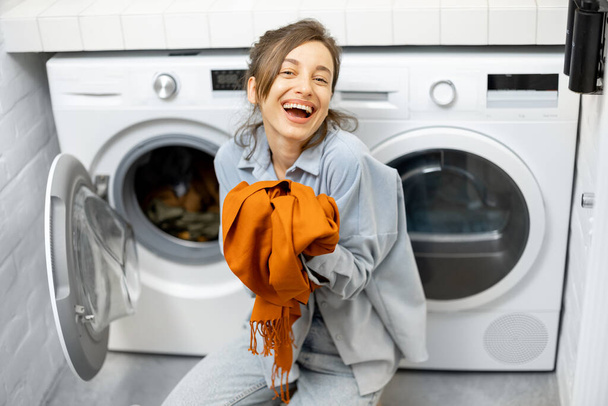 Ama de casa con bufanda limpia fresca en el cuarto de lavado en casa - Foto, imagen