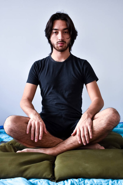 young man doing yoga at home. butterfly position. long-haired man. - Photo, Image