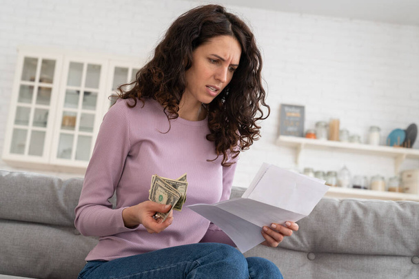 Smutná mladá dívka drží poslední hotovost peníze pocit úzkosti z dluhů nebo bankrotu, sedí doma. - Fotografie, Obrázek