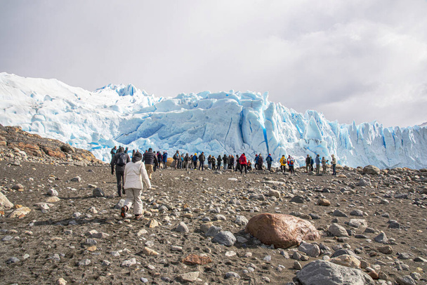 группа людей выстроилась в линию, поднимаясь по льду на вершину ледника Перито-Морено в Патагонии, Аргентина - Фото, изображение