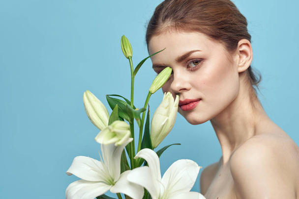 encantadora mujer con flores blancas sobre fondo azul retrato vista recortada - Foto, Imagen