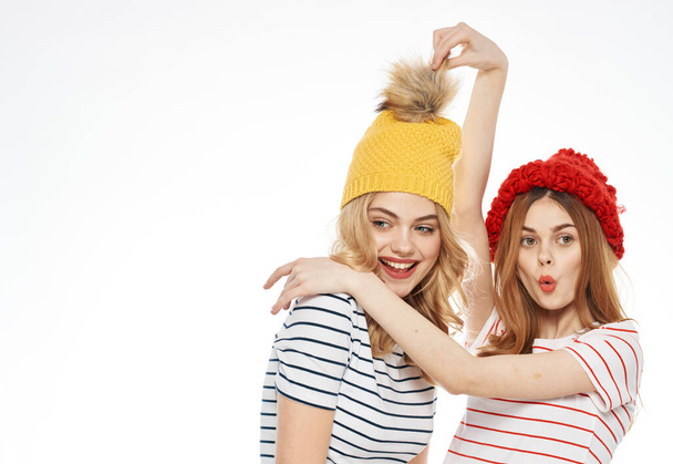 Cheerful girlfriends striped t-shirts multicolored caps emotions joy cropped view studio - Foto, Bild