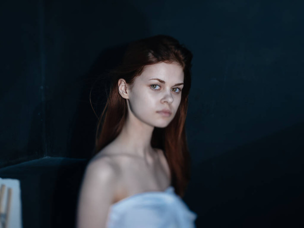 Vrouw met een geinteresseerde blik op een donkere achtergrond zijaanzicht model - Foto, afbeelding