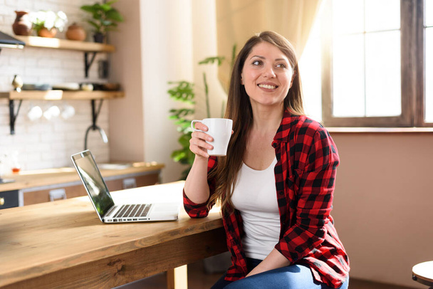 Vrouw surft op internet met haar laptop met een wit scherm. Ze werkt thuis als slim werkster. - Foto, afbeelding