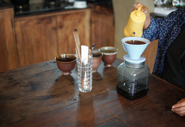 бариста готовит кофе с кофеваркой и капельным чайником. Капельный молотый кофе с фильтром - Фото, изображение