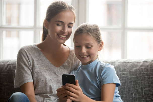 Feliz mamá y su hija utilizan gadget smartphone - Foto, Imagen