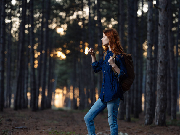 Счастливая рыжая женщина в голубой рубашке путешествует в сосновом лесу на природе - Фото, изображение