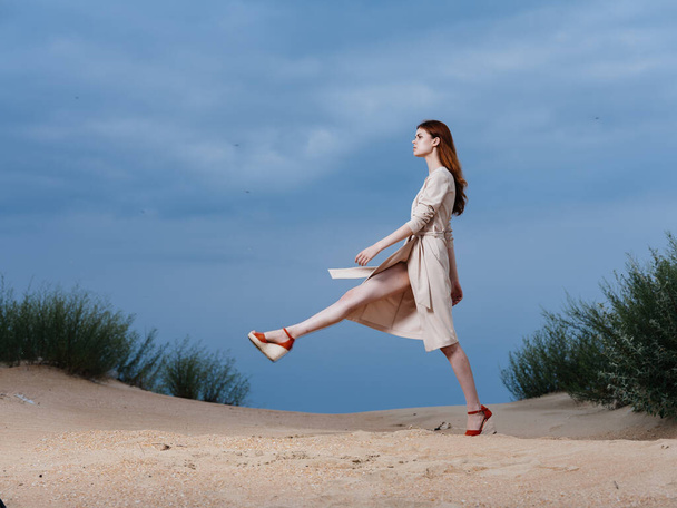 Μια γυναίκα σε ένα μπεζ φόρεμα περπατά με ένα μακρύ διασκελισμό στην παραλία - Φωτογραφία, εικόνα