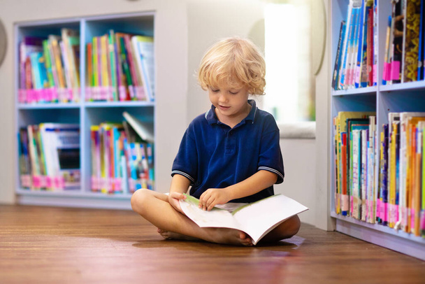 Child in school library. Kids read books. Little boy reading and studying. Children at book store. Smart intelligent preschool kid choosing books to borrow. - Fotó, kép