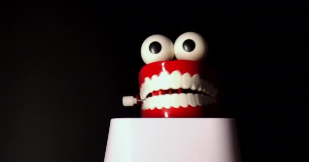 Een glimlachende speelgoedprothese, met witte tanden en grote ogen geïsoleerd tegen een zwarte achtergrond. - Video