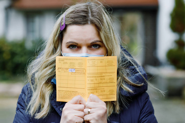Donna con maschera medica in possesso di certificato internazionale tedesco della vaccinazione. Adulti che mostrano le informazioni sul vaccino contro il virus della covd 19 corona. - Foto, immagini
