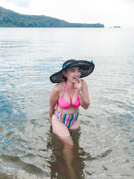 A flirty asian woman giggles while taking a dip at the beach. - Фото, зображення