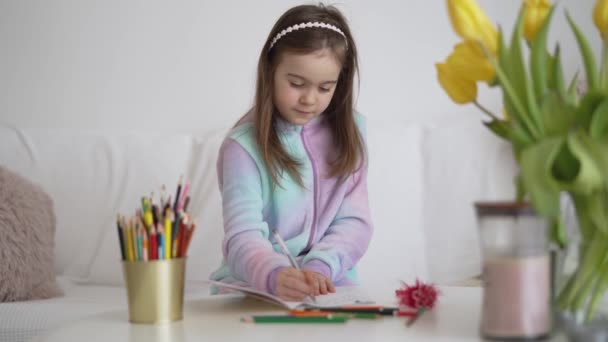 Девушка пишет в блокноте рядом с цветами - Кадры, видео