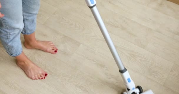 Onherkenbare vrouw met behulp van moderne stofzuiger om stof te verwijderen van de vloer, terwijl het opruimen van de kamer thuis, vrouw vrouw doet dagelijkse schoonmaak routine. - Video