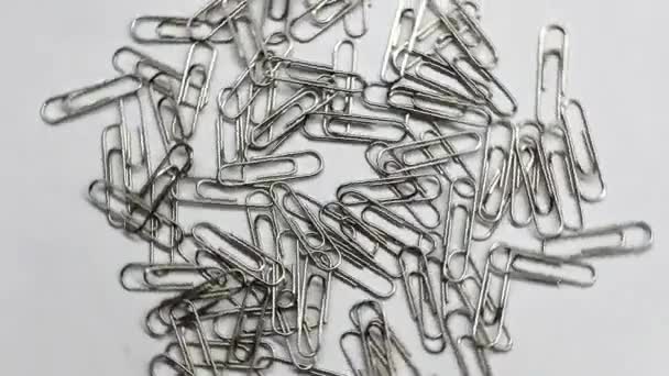 A lot of paper clips on a white background. Spinning objects. Rotating objects - Footage, Video