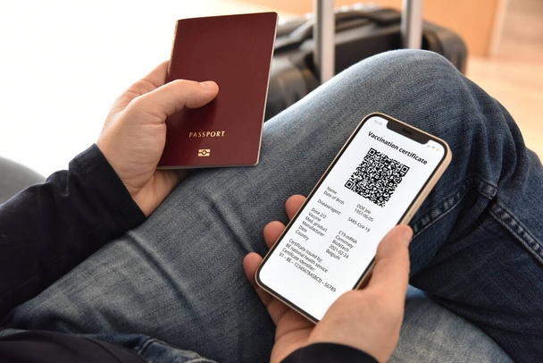 Man holding passport and mobile phone with digital certificate of vaccination against Covid-19, a negative PCR test or recovery from Covid-19. Travel concept during coronavirus pandemic. - Photo, Image