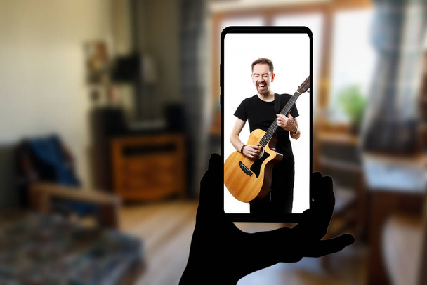 Online-Musikdarbietungen des Sängers zu Hause per Smartphone verfolgen. Musikvideo im Live-Stream - Foto, Bild