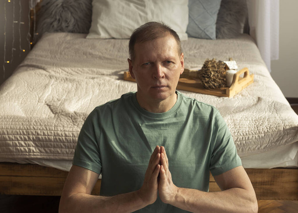 Middle aged man practicing yoga and meditation at eco home. Lifestyle and meditating. - Foto, afbeelding