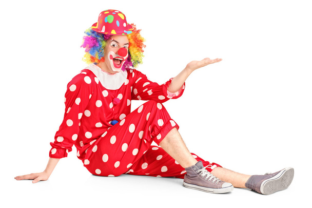 Clown with smiling joyful expression sitting down and gesturing - 写真・画像